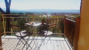 Enjoy a serene view of the surrounding hills from this balcony, featuring a table and two chairs.