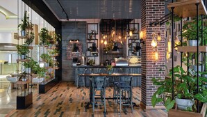 A modern kitchen with a brick wall, hanging plants, and a wooden dining area. - Holiday Inn Cairo Maadi (Cairo)