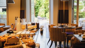 A modern dining area with a long table, multiple chairs, and pendant lighting. - Hôtel Le d'Avaugour (Dinan)