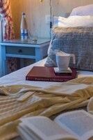 Una cama bien hecha con un libro titulado 'Portraits d'Hôtels' y una taza de café sobre un posavasos.