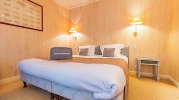Habitació d'hotel amb un llit gran, dues làmpades al costat del llit, una taula de nit petita i un quadre amb marc a la paret.