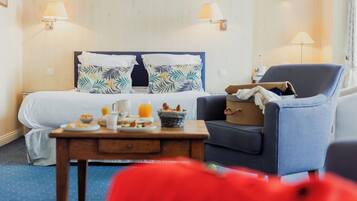 Een hotelkamer met een bed, een stoel, een tafel met ontbijtartikelen en wandlampen.