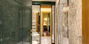 Une salle de bain moderne avec une douche à parois de verre, des toilettes et un sol carrelé en marbre.