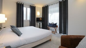 A hotel room with a large bed, a desk, a chair, and a TV. - Hôtel Restaurant Novalaise Plage (Novalaise)