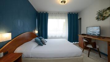 Un dormitorio con cama, escritorio, silla y televisor.