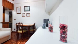 Un coin repas avec une table et des chaises en bois, un canapé blanc et des tableaux encadrés accrochés au mur.