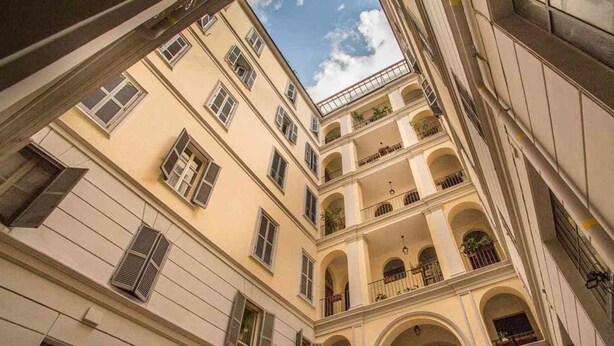 Un edificio de varios pisos con balcones y ventanas arqueadas.