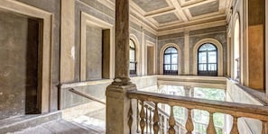 Un interno con balcone, colonne e finestre ad arco.