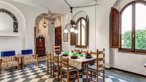 A dining area with a checkered floor, wooden chairs, a table set for four, and large windows with arched tops. - Campo de Fiori 3 bedroom apartment (Rome)