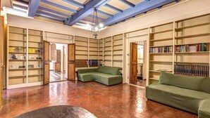 A spacious room with high ceilings, exposed beams, and a large collection of bookshelves. - Campo de Fiori 3 bedroom apartment (Rome)