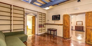 Una stanza con un divano verde, un armadietto in legno e un pavimento piastrellato.