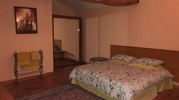 A bedroom with a bed, a chair, a mirror, and a painting on the wall.