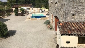 A courtyard with a swimming pool, stone buildings, and a gravel path. - Chambre d'hôtes Les Cygnes Noirs (Aujac)