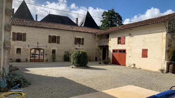 A courtyard with stone buildings, a gravel ground, and a covered seating area. - Chambre d'hôtes Les Cygnes Noirs (Aujac)