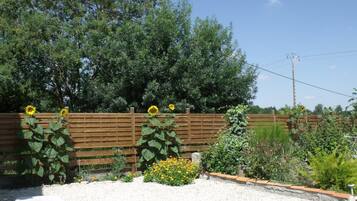 A garden with a wooden fence, a gravel area, and a white chair.