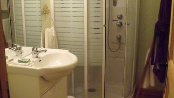 A bathroom with a glass-enclosed shower, a sink, and a toilet.