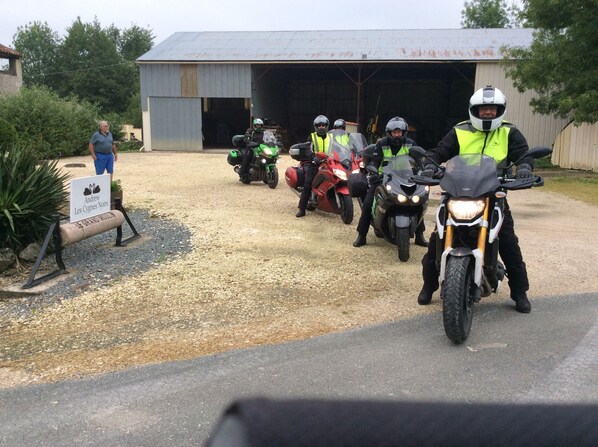 A group of motorcyclists lined up in front of a building with a sign that reads "Andrew Les Cygnes Noirs". - Chambre d'hôtes Les Cygnes Noirs (Aujac)