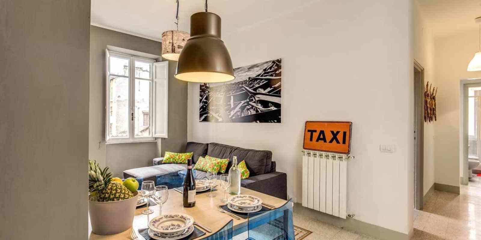 A dining area with a table set for four, a sofa, and a 'TAXI' sign on the wall.