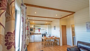 Eine gemütliche Küche mit Holzbalken, ein Essbereich mit Tisch und Stühlen und ein Wohnzimmer mit Ledersofa.