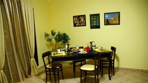 A dining area with a table set for four, chairs, a potted plant, and wall art. - B&B Portagibli (Salemi)