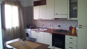 A compact kitchen with a washing machine, a sink, and a stove. - B&B Portagibli (Salemi)
