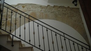 A staircase with a stone wall backdrop and a black metal railing. - B&B Portagibli (Salemi)