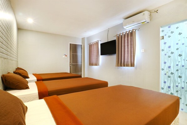 Habitación de hotel con dos camas individuales, televisión, unidad de aire acondicionado y cortina estampada.