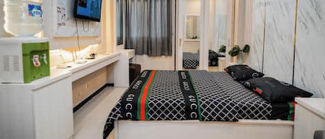 A modern bedroom with a bed, a desk, a TV, and a wardrobe.