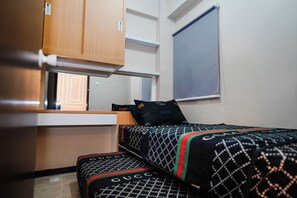 A compact room with a bed, a small desk, and a window.