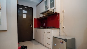 A compact kitchen with a refrigerator, a sink, and cabinets. - The Suites Metro Apartment - King Property (Bandung)