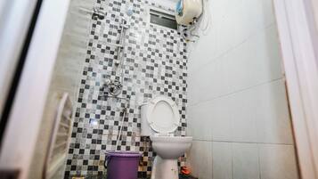 A small bathroom with a toilet, a shower, and a tiled wall.