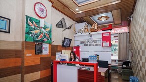 Un mostrador de recepción con marco rojo, un reloj y varias decoraciones en la pared, incluyendo una pintura de carpas koi y trofeos.