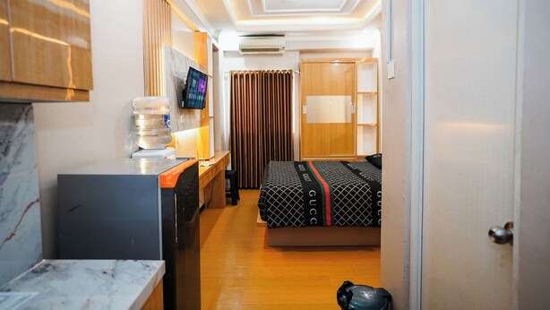 Una habitación de hotel con un escritorio de madera, una cama con ropa de cama estampada, un televisor y un armario.