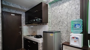 A compact kitchen with a refrigerator, a water dispenser, and a sink. - The Suites Metro Apartment - King Property (Bandung)