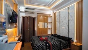 A hotel room with a bed, a desk, a mirror, a wardrobe, and a television. - The Suites Metro Apartment - King Property (Bandung)