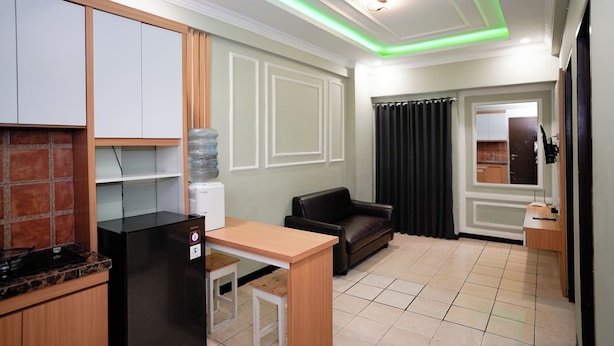 A compact kitchen with a refrigerator, a water dispenser, and a countertop. - The Suites Metro Apartment - King Property (Bandung)