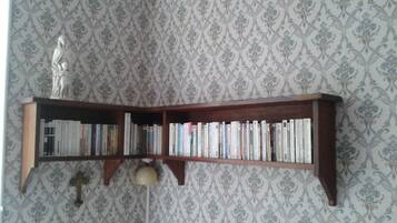 A corner bookshelf with books and a statue.