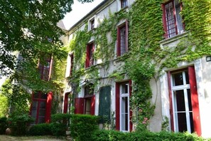 Ein Gebäude mit roten Fensterläden und einer mit Efeu bewachsenen Fassade.