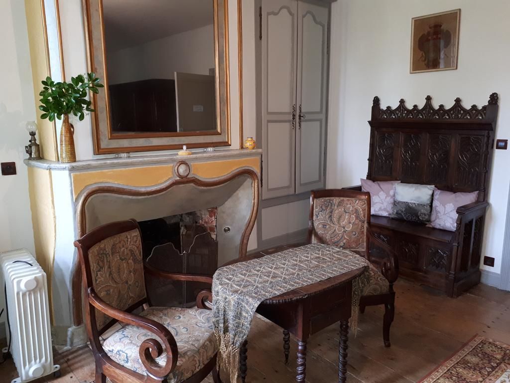 Ein Zimmer mit Holzstuhl, kleinem Tisch, Spiegel, Heizkörper und einem Schrank mit gemustertem Kissen.