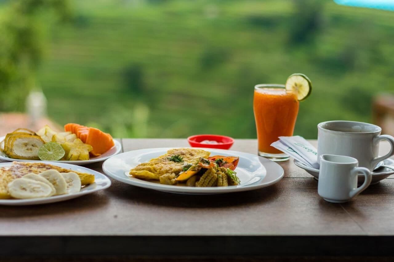 Una mesa de desayuno con platos de comida, un vaso de jugo y una taza.