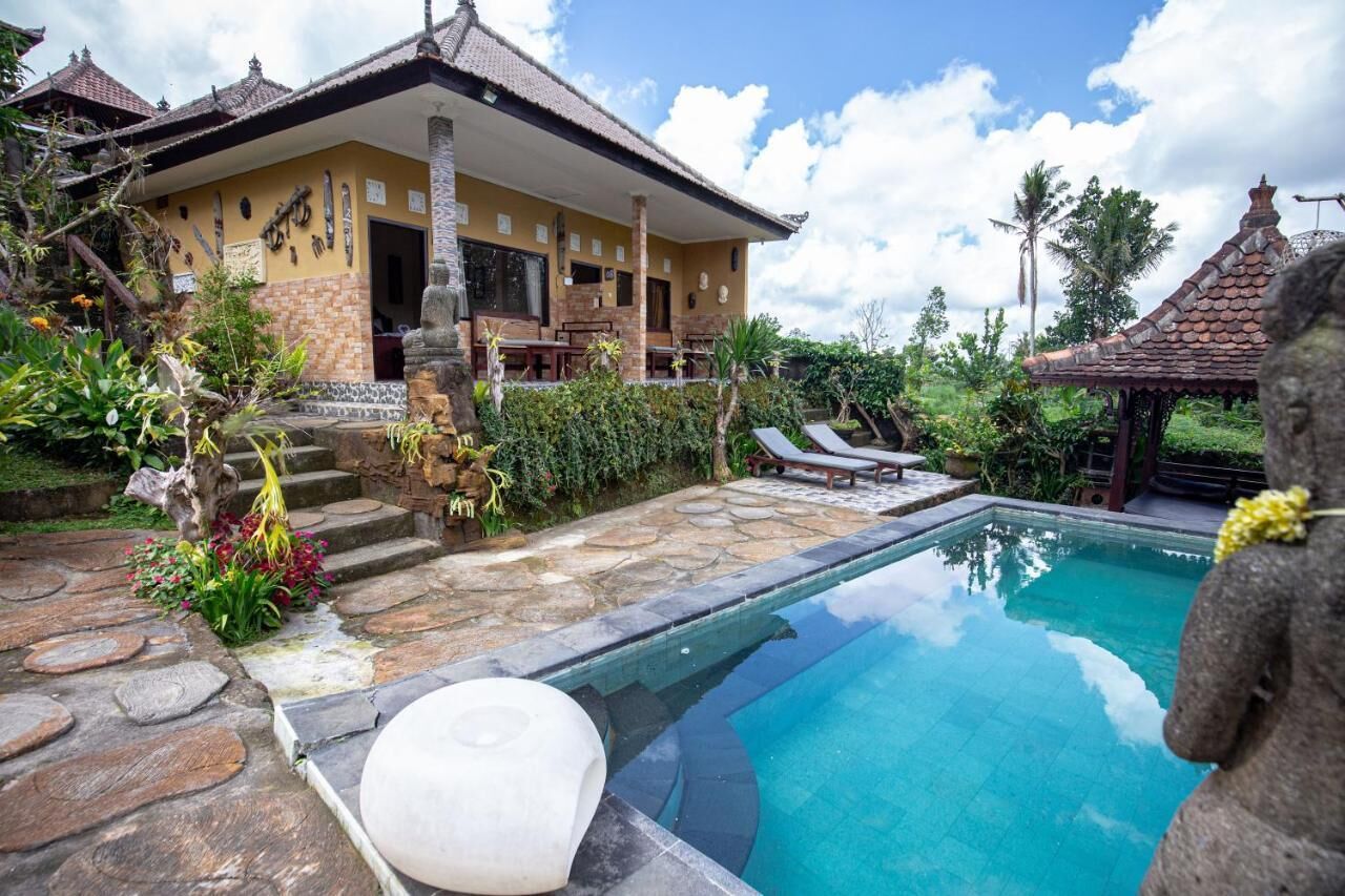 A poolside area with a stone pathway leading to a building with a tiled roof.
