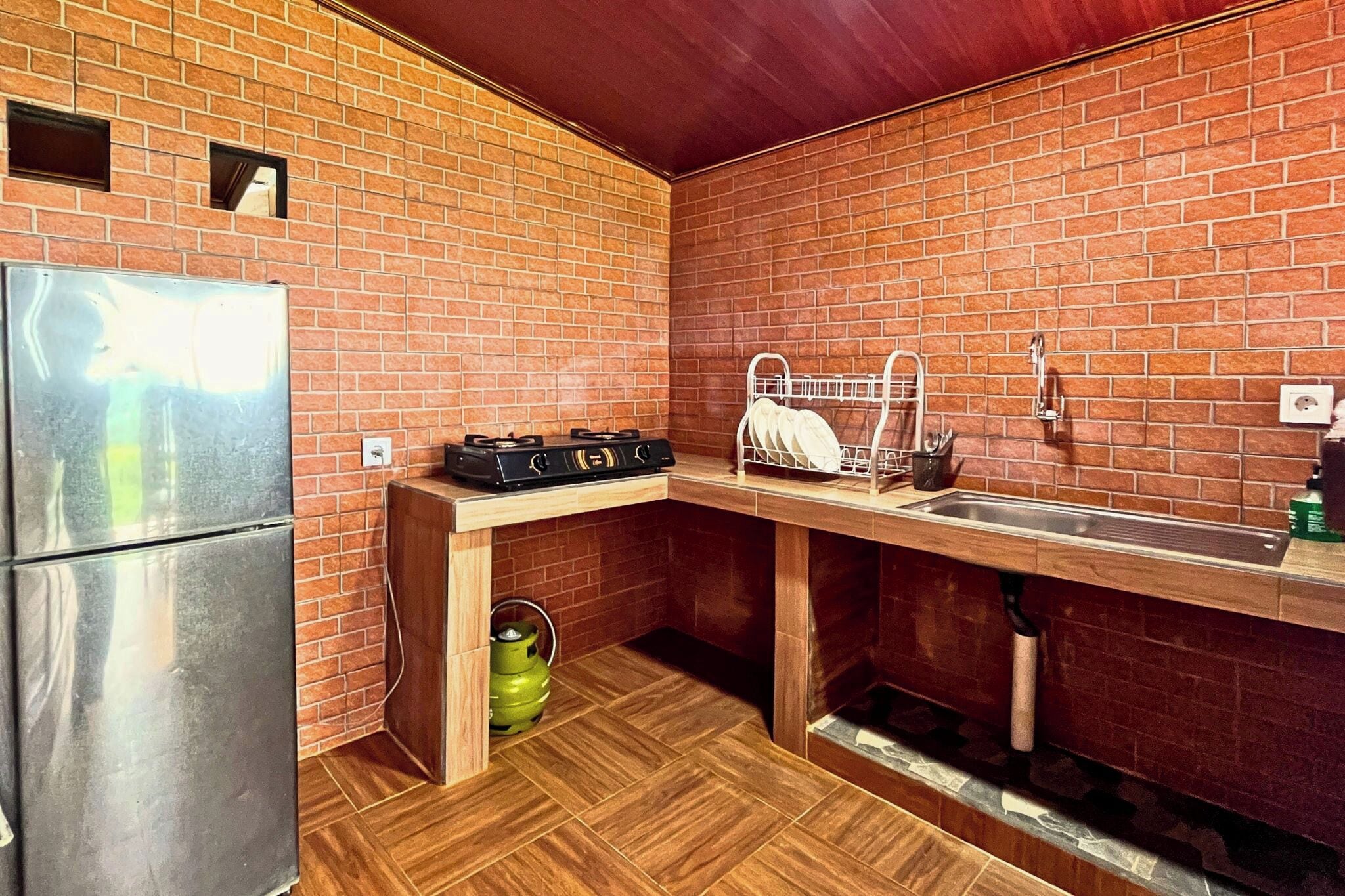 A compact kitchen with a brick backsplash, stainless steel appliances, and a wooden countertop.