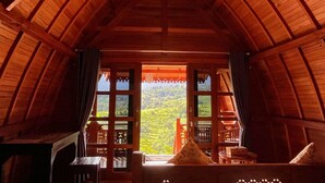 Una habitación acogedora de madera con un ventanal que ofrece vistas a un paisaje verde exuberante.
