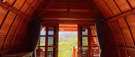 Una habitación acogedora de madera con un ventanal que ofrece vistas a un paisaje verde exuberante.