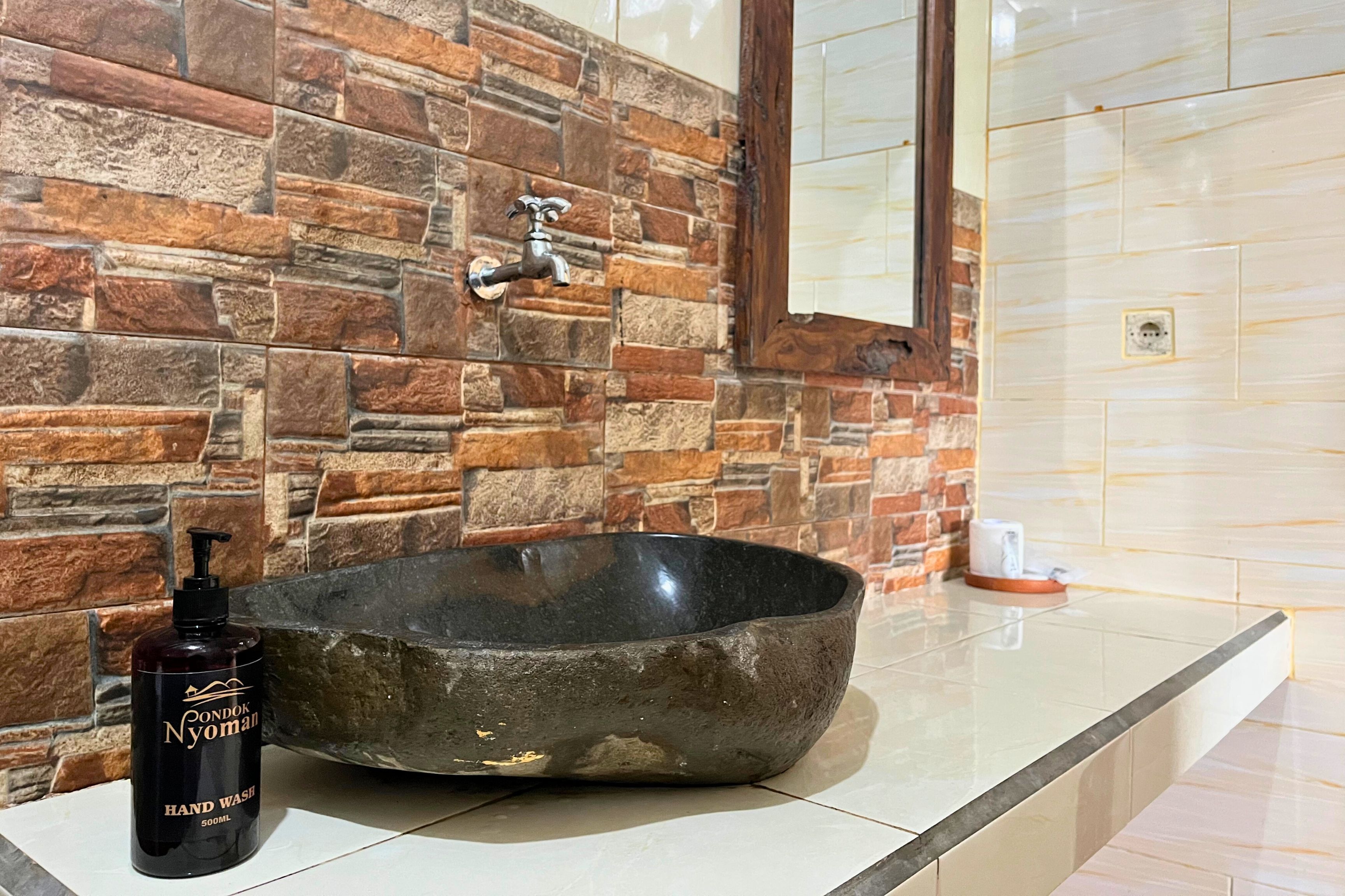 Un baño con lavamanos de piedra, dispensador de jabón y grifo.