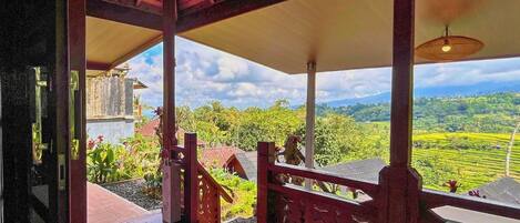 A wooden deck with a view of a lush green landscape and distant hills.