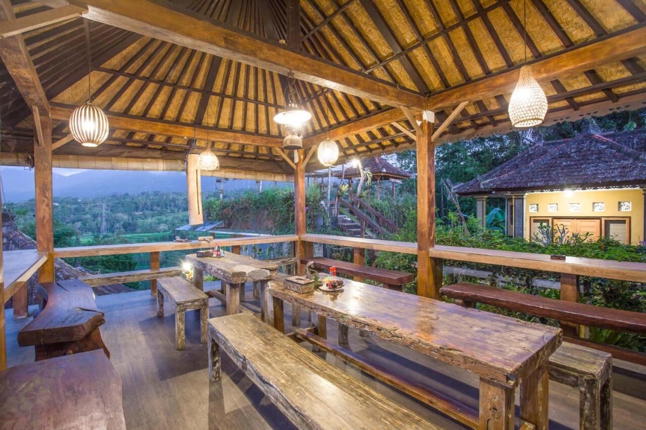 Una terraza de madera al aire libre con bancos y mesas, con vistas a un paisaje pintoresco.