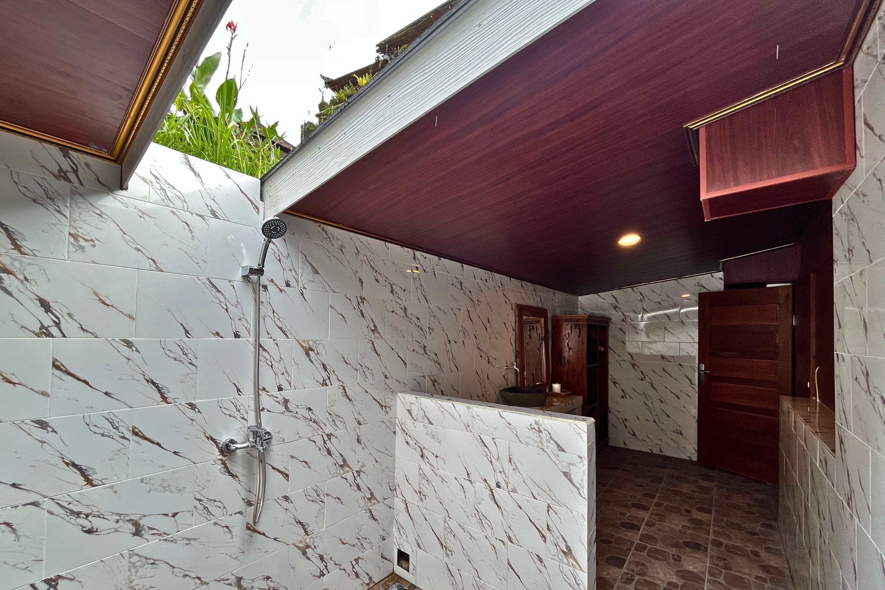 A bathroom with marble tiles, a shower, and a wooden door.