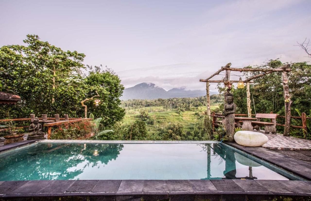 Un espace piscine extérieur paisible, offrant une vue sur une vallée verdoyante et des montagnes en arrière-plan.