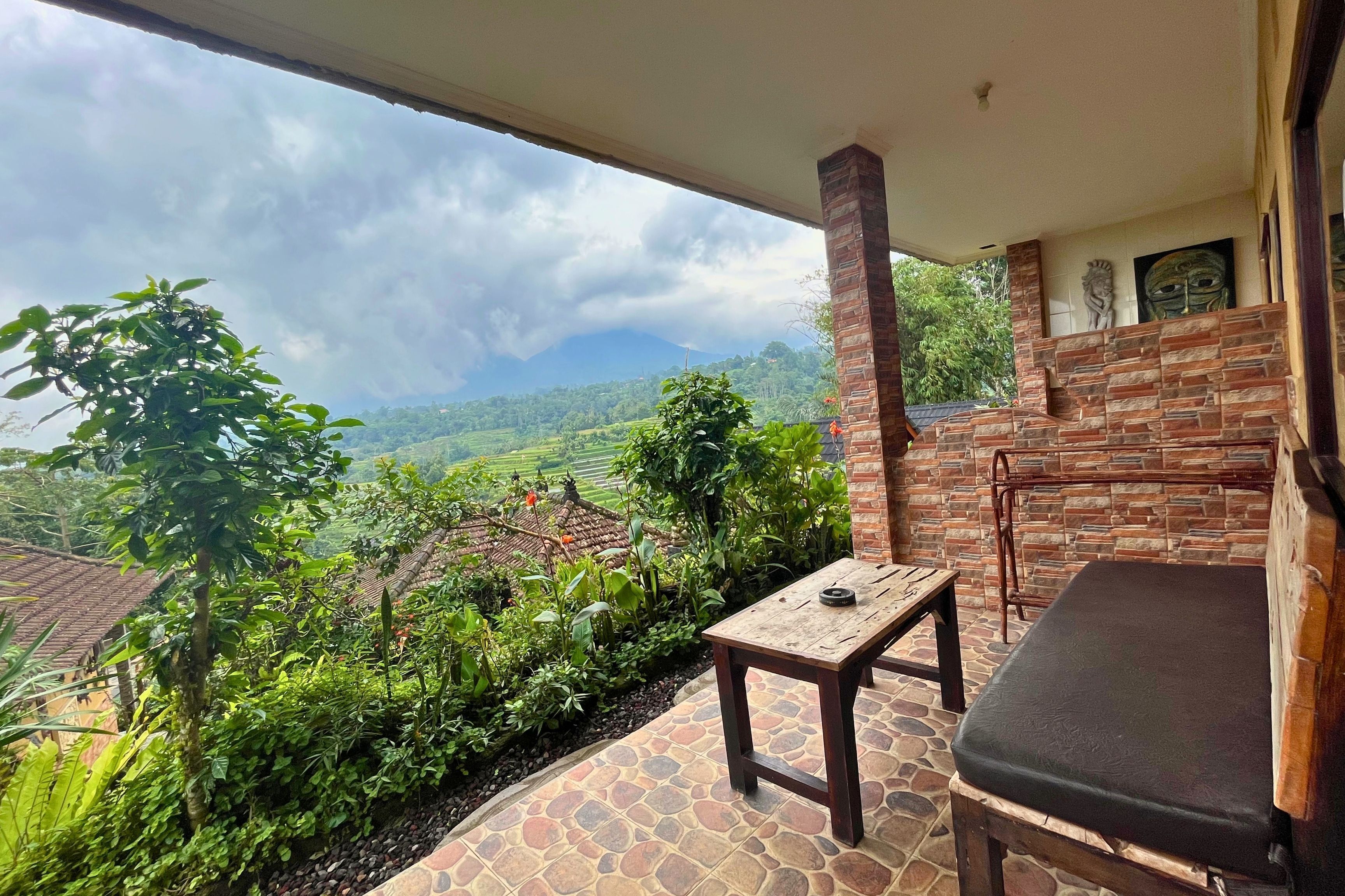 A balcony with a stone floor, a wooden table, and a cushioned bench.